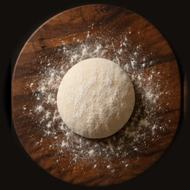 A dough ball on a floured wooden board, seen from above