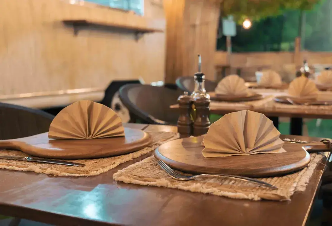 Tables set with wooden boards and folded napkins