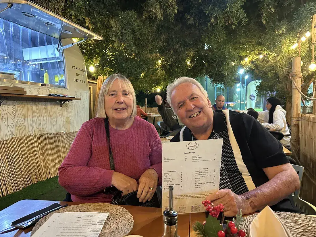 A smiling couple at their table holding the menu